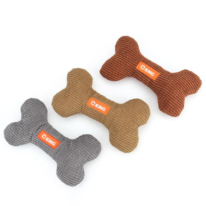 Three bone-shaped dog toys in gray, brown, and orange on a white background