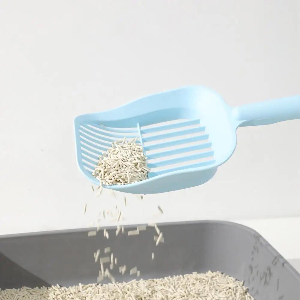 Blue plastic scoop with cat litter over a gray litter box on a white background